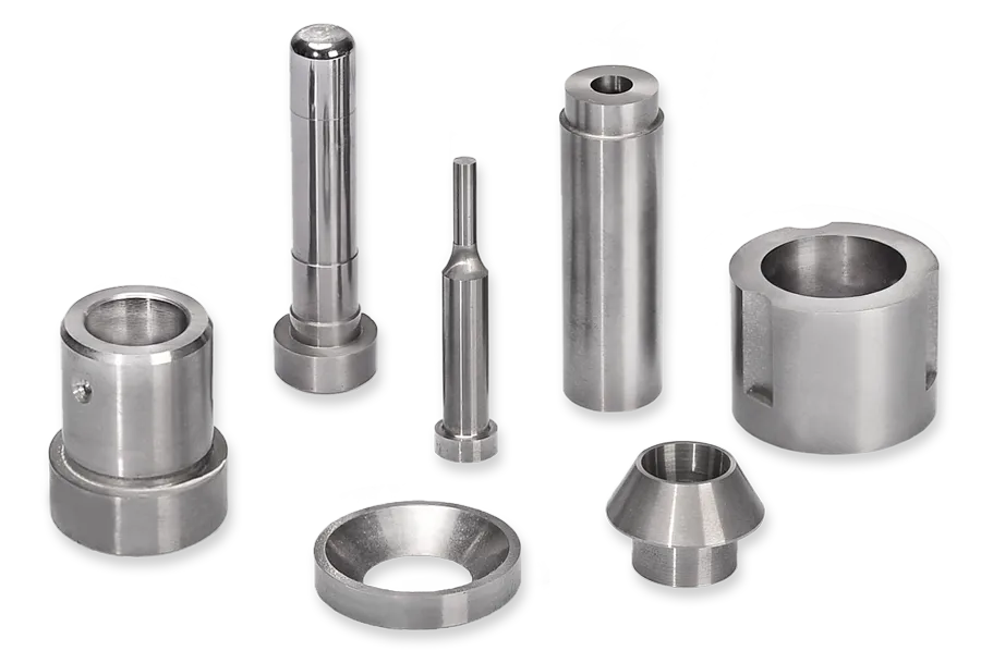 Sieben präzisionsgefertigte Metallteile aus Hartmetall (HM) für Schnitt- und Stanzwerkzeuge nach Zeichnung gefertigt. Unterschiedlicher Form und Größe, darunter zylindrische Stangen, Ringe.