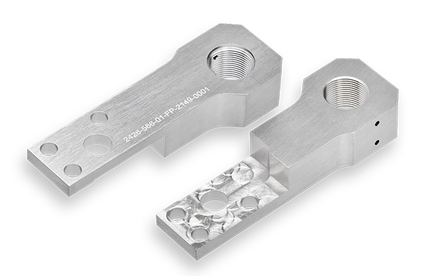 Zwei Sensorhalter gefertigt aus Wolfram-Schwermetall (WSM) Sorte SM18F. Die Teile sind in zwei unterschiedlichen Ansichten von oben und unten zu sehen.