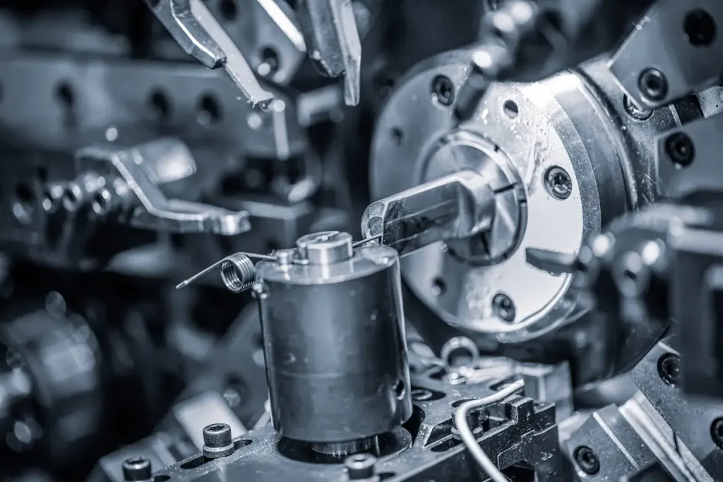 Nahaufnahme einer komplizierten Industriemaschine mit verschiedenen Metallkomponenten, Zahnrädern und Werkzeugen in komplizierter Anordnung, die einen komplexen mechanischen Prozess in der Fertigung oder im Maschinenbau veranschaulicht.