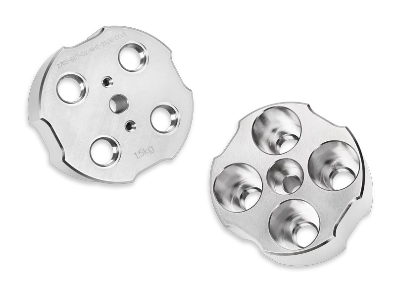 Zwei Dämpfungsmassen gefertigt aus WSM Wolfram-Schwermetall. Aus unterschiedlichen Ansichten mit Ausparungen und Vertiefungen.